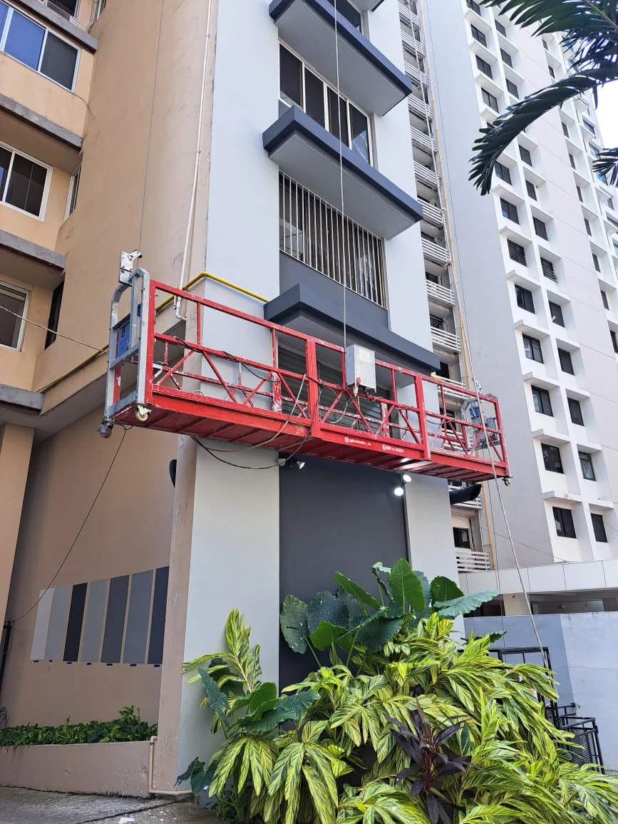 Guindola suspendida trabajando en la fachada de un edificio residencial